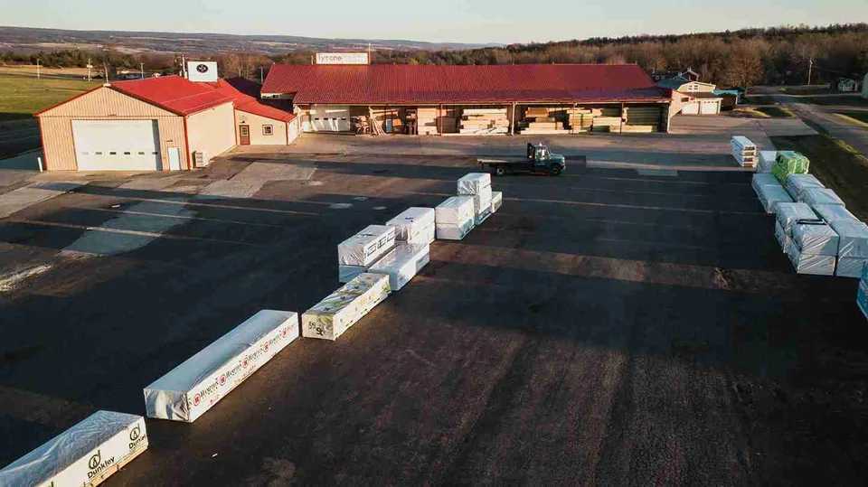 Tyrone Building Supply in 2020, with red-roofed storage buildings and bundled lumber in the yard